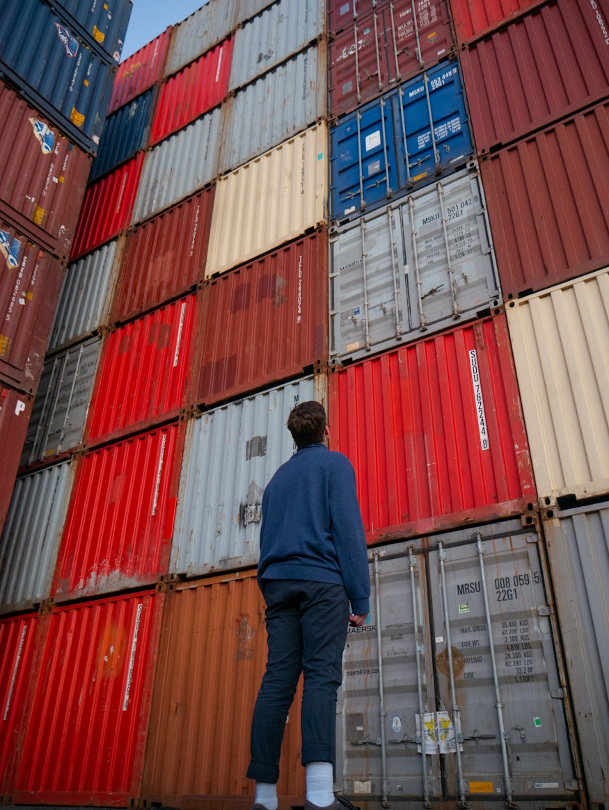 Person standing in front of stacked shipping containers
